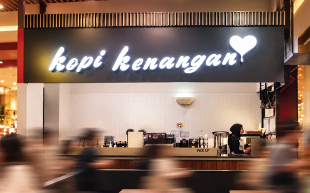 Konter gerai Kopi Kenangan dengan papan nama neon yang menyala